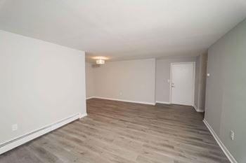 An empty living room with wood floors and white walls